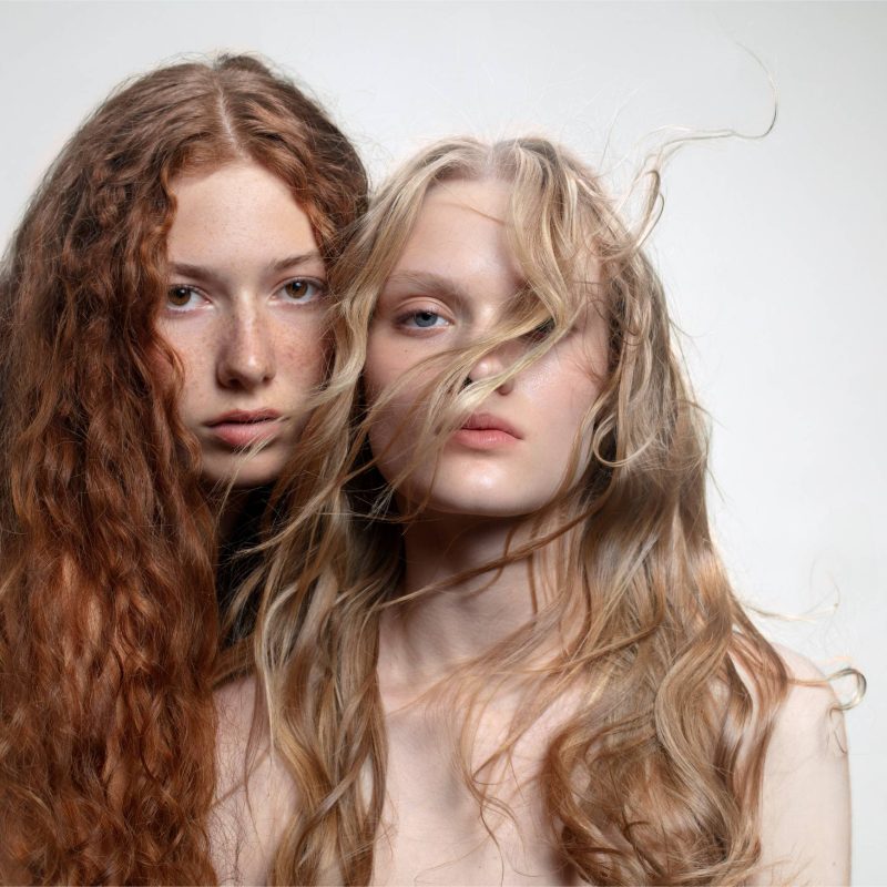 Donne bionde e rosse che guardano la fotocamera, rappresentando diversi tipi di capelli per una routine di cura dei capelli